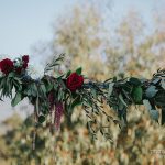 Deep red flowers on wedding arch